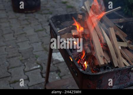 Morceaux de bois empilés dans un grill brûlant dans un feu d'orange.Préparation du gril la nuit.Heure du dîner. Banque D'Images