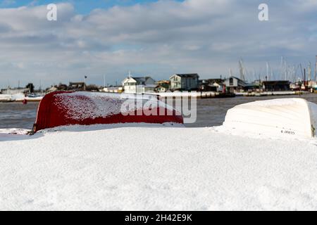Des bateaux à rames ont été laissés amarrés sur la plage sur la côte du Suffolk.Ils ont été couverts de neige après une rare tempête de neige qui couvre la région Banque D'Images