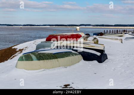 Des bateaux à rames ont été laissés amarrés sur la plage sur la côte du Suffolk.Ils ont été couverts de neige après une rare tempête de neige qui couvre la région Banque D'Images
