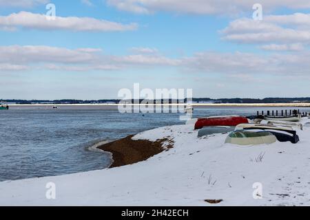 Des bateaux à rames ont été laissés amarrés sur la plage sur la côte du Suffolk.Ils ont été couverts de neige après une rare tempête de neige qui couvre la région Banque D'Images