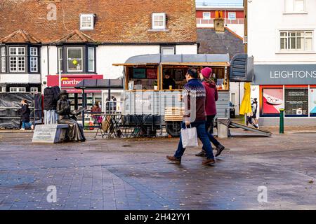 Epsom Surrey Londres, Royaume-Uni, octobre 31 2021, deux personnes marchant devant Un marché éclair Takeaway café Staall porte sac de shopping Banque D'Images