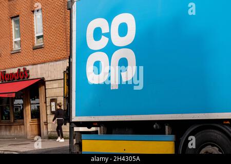 Epsom Surrey Londres, Royaume-Uni, octobre 31 2021, camion ou camion de livraison de nourriture Co-Op passant Un restaurant Nando's avec Une femme marchant passé Banque D'Images