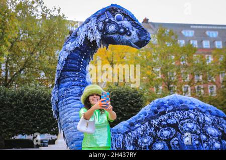 Grosvenor Square, Londres, Royaume-Uni.31 octobre 2021.Les gens regardent et posent avec désordre le monstre NESS de COP.Le désordre est entièrement fait à partir de jeans recyclés et d'autres matériaux durables, et sera sur Grosvenor Square jusqu'à novembre 12.La sculpture est une collaboration entre l'artiste Billie Achilleos, plate-forme de streaming WaterBear et MUD Jeans, une marque circulaire de denim.Credit: Imagetraceur/Alamy Live News Banque D'Images