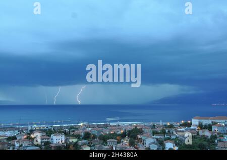 Tempête approchant la ville maritime de Rijeka en Croatie depuis le golfe de Rijeka.Tempête de foudre sur la ville.La foudre frappe sur le ciel bleu foncé dans la ville de nuit Banque D'Images