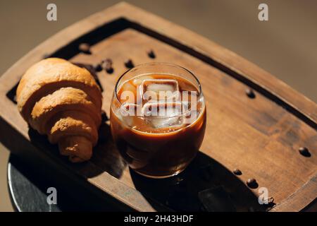 Verre de café glacé savoureux avec lait et croissant sur la table Banque D'Images