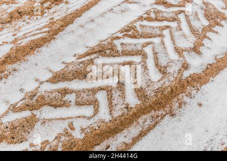 Traces et motifs des pneus des roues de transport industriel sur le sol en hiver. Banque D'Images