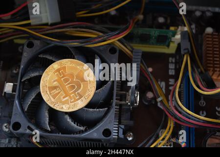 Un bitcoin sur le ventilateur de refroidissement du processeur d'un ordinateur sale et ancien. Banque D'Images