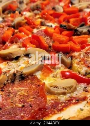 Gros plan de pepperoni et de champignons avec poivrons rouges sur une pizza Banque D'Images