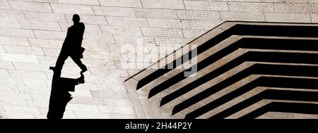 Silhouette d'ombre d'un homme marchant ville rue trottoir avec des escaliers, en noir et blanc sépia d'en haut Banque D'Images