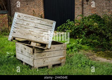 Caisses de fruits en bois empilées les unes sur les autres sur l'herbe à l'extérieur du bâtiment de ferme Banque D'Images