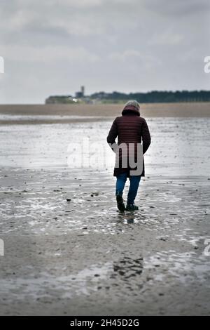 femme marchant sur la plage à marée basse holme nord norfolk angleterre Banque D'Images