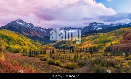 Une vallée colorée avec la fourche est de Dallas Creek avec des couleurs d'automne spectaculaires sous le mont Sneffels et des nuages de coucher de soleil dans les montagnes de San Juan.