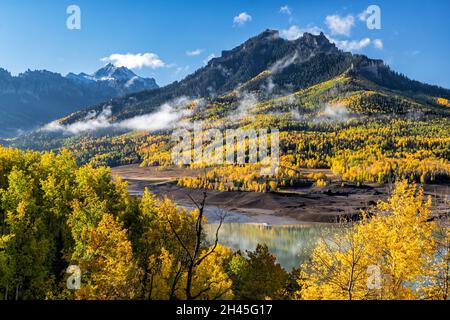 Des nuages bas pendent sur la crête de Cimarron et les montagnes avec un tapis de feuillage d'automne dans la forêt nationale d'Uncompahgre au-dessus du Silver Jack Reservoi Banque D'Images