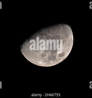 Une lune Gibbous cirant contre le ciel noir Banque D'Images