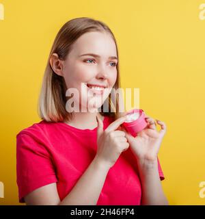 Happy Smiling Woman Portrait application crème hydratante main crème look côté sur l'espace de copie. Adolescente utilisant un produit cosmétique de soin de la peau isolée Banque D'Images