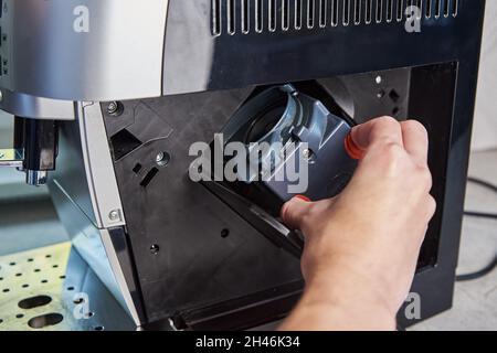 Nettoyage automatique de la machine à café.La femme insère le mécanisme dans la machine à café.Entretien des appareils ménagers Banque D'Images