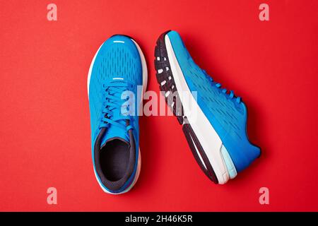 Baskets de running bleues sur fond rouge.Paire de chaussures de sport pour hommes pour le fitness, vue du dessus Banque D'Images