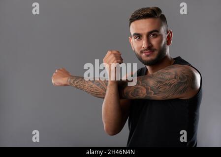 Portrait de la belle tenue jeune homme étirant les bras avant de travailler avec des poids lourds Banque D'Images