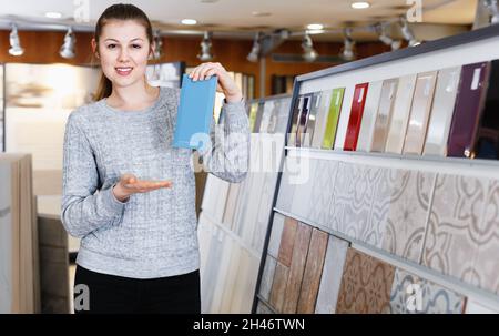 Portrait d'une femme regardant un échantillon de carreaux de céramique en magasin Banque D'Images