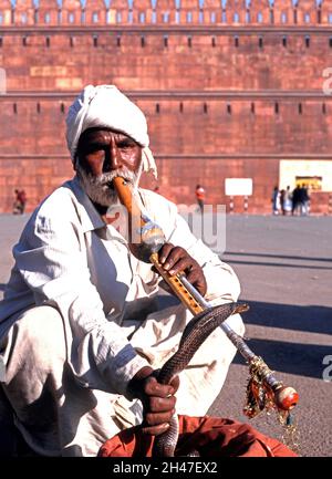 Charmeur de serpents les serpents tentants de cobra hors de leurs paniers en osier à l'extérieur du fort Rouge, Delhi, Inde Banque D'Images