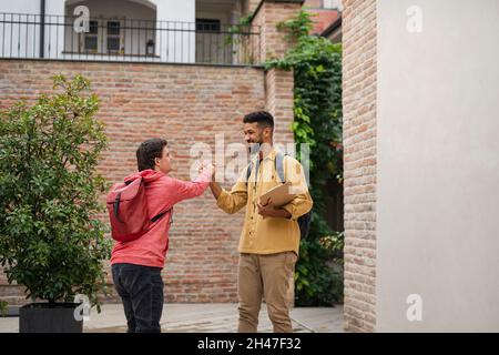 Jeune homme avec le syndrome de Down et son ami de mentorat rencontre et salutation à l'extérieur Banque D'Images