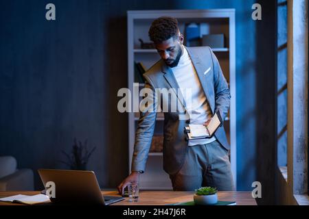 Jeune homme d'affaires afro-américain avec journal à l'intérieur dans le bureau la nuit. Banque D'Images