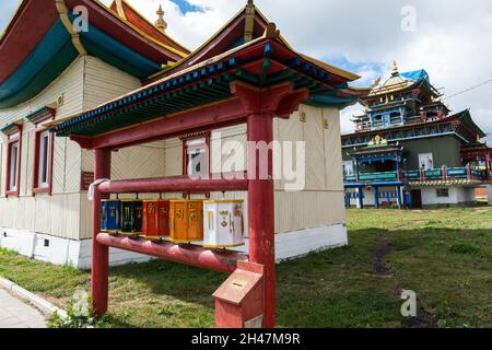 Rangée de roues de prière devant un dugan et le Temple Etigel Khambin en arrière-plan.Ivolginsky Datsan, Buryatia, Russie Banque D'Images