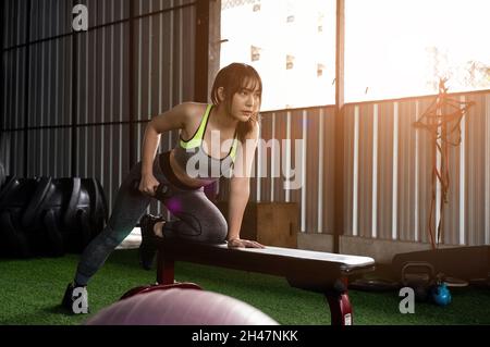 Une femme asiatique stupéfiante se concentre sur lever un haltère à la salle de gym. Musculation Banque D'Images