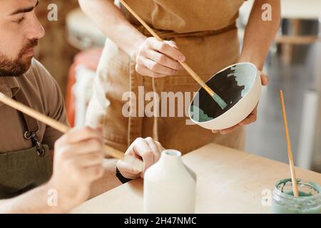 Gros plan de deux jeunes artistes décorant la céramique dans l'atelier de poterie, l'espace de copie Banque D'Images