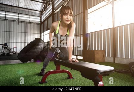 Une femme asiatique stupéfiante se concentre sur lever un haltère à la salle de gym. Musculation Banque D'Images