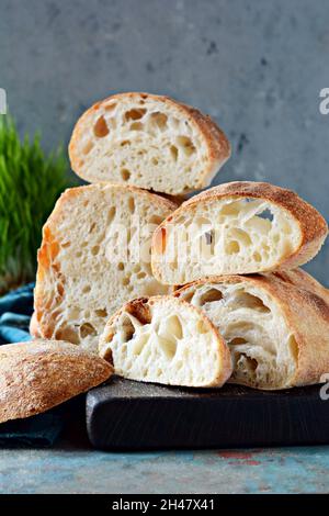 Ciabatta italienne fraîche avec croûte croustillante, miettes humides et gros pores sur fond bleu clair.Pain de levain fait maison (sans levure).Équilibre alimentaire. Banque D'Images