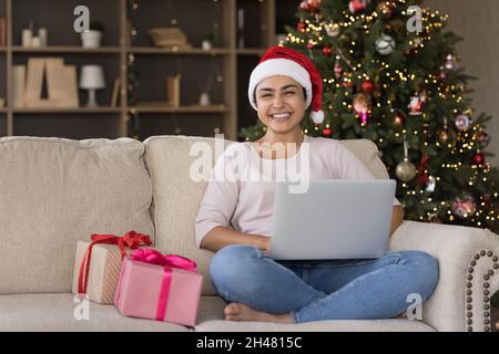 Bonne femme indienne millénaire utilisant l'ordinateur à la maison. Banque D'Images