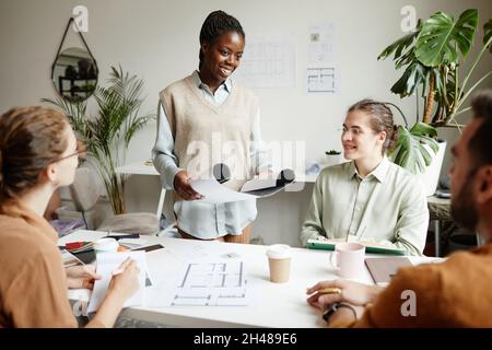 Portrait d'une jeune femme souriante présentant le projet à l'équipe de conception créative en studio, espace de copie Banque D'Images