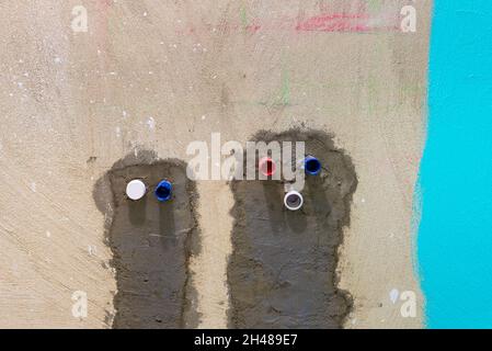 Eau chaude et froide et tuyaux d'égout sortant du mur dans la salle de bains Banque D'Images