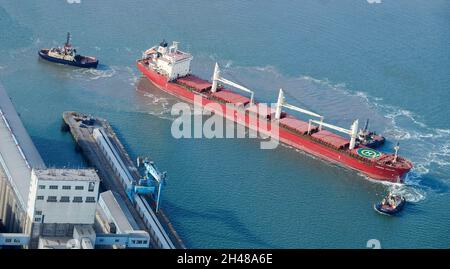 Bateau entre deux remorqueurs en cours de guidage dans Seaforth Docks, Liverpool, Merseyside, nord-ouest de l'Angleterre, Royaume-Uni Banque D'Images