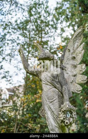 Vue de face de la statue commémorative de l'ange de pierre avec ailes, isolée dans un cimetière d'église britannique. Banque D'Images