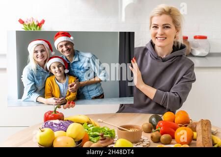 Photo imprimée sur toile, fond blanc.Bonne famille en chapeaux de père Noël célébrant Noël à la maison Banque D'Images