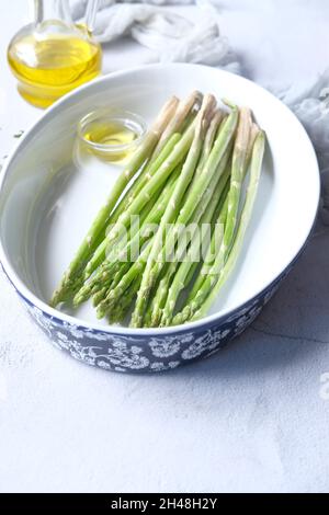 Asperges vertes dans un bol avec de l'huile sur la table Banque D'Images