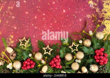 Fond décoratif de Noël avec boule d'or étincelante et boules étoiles, houx et verdure d'hiver.Composition festive pour les fêtes.Haut Banque D'Images