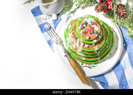 Pile de crêpes vertes pour le petit déjeuner, comme un arbre de Noël avec des saupoudrés de sucre.Petit déjeuner de Noël festif sur table décorée de Noël et de nouvel an Banque D'Images