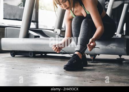 Gros plan de la jeune femme asiatique laçage chaussures de sport avant l'exercice à la salle de gym. Banque D'Images