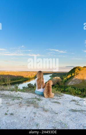 un chien de sharpey sur le fond d'un paysage de rivière de montagne. le chien marche avec le propriétaire au coucher du soleil. sharpey. embrassant un chien, amour animal de compagnie d'amitié. Banque D'Images