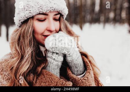 Belle jeune femme dans une forêt enneigée d'hiver.Fille portant des gants, une casquette et un manteau molletonnés.Forêt de Noël, arbres sur fond flou.Croisé Banque D'Images