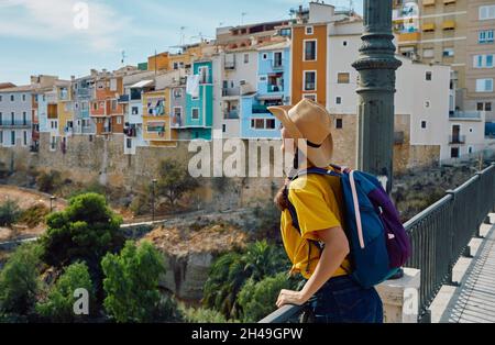 Concept de voyage. Voyageur dans un chapeau de paille regardant la belle ville de Villajoyosa avec de belles maisons colorées et des bâtiments Banque D'Images