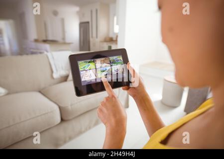 Femme asiatique utilisant une tablette avec la vue des caméras de sécurité à la maison Banque D'Images