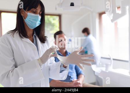 Dentiste biracial féminin portant des gants médicaux et patient mâle attendant à la clinique dentaire moderne Banque D'Images