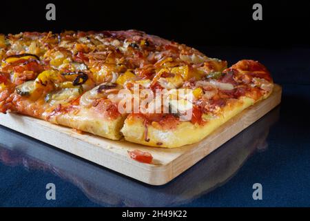 La pizza avec saucisse et fromage sur fond noir. Cuisson sur table. Produits de l'alimentation Banque D'Images