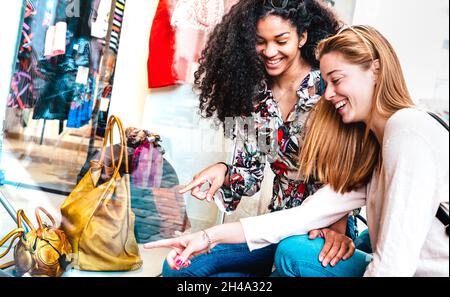 Jeunes femmes heureuses regardant l'exposition à la boutique moda de la semaine de la mode - meilleures amies partageant du temps libre ayant des achats amusants dans le centre-ville Banque D'Images