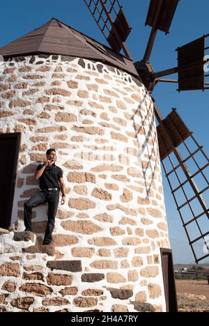 homme s'inclinant sur le mur d'un moulin à vent Banque D'Images