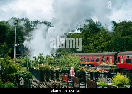 Man se tient debout pour regarder un train à vapeur passer en entrant dans le tunnel de Grosmont, Grosmont, North York Moors National Park, Royaume-Uni Banque D'Images